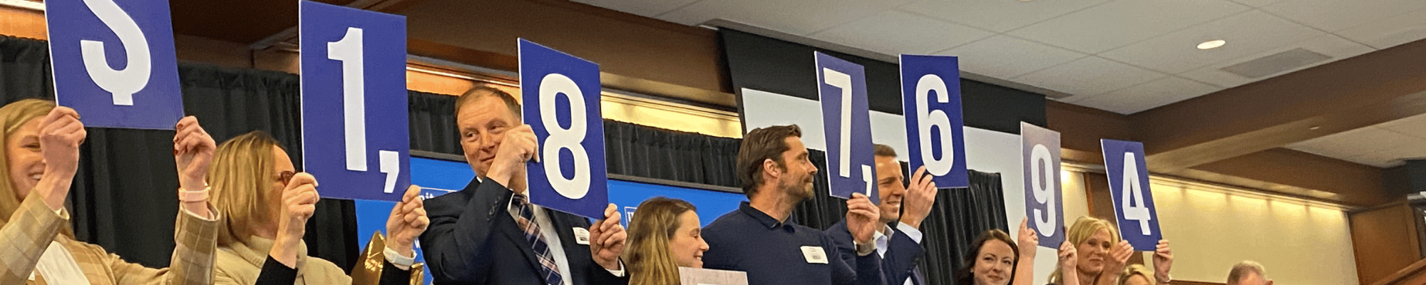 Photo of United Way volunteers holding blue numbers that show how much money the 2022 campaign raised, $1,877,694